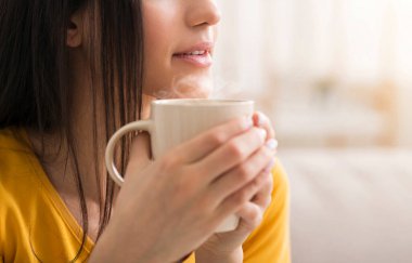 Evinde bir fincan sıcak içecekle genç bir kadının yakın görüntüsü, boş bir alan. Panorama