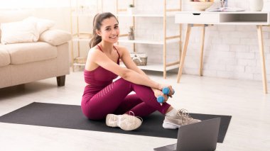 Evde eğitim. Dambılı gülümseyen Latin kadın aydınlık odada egzersiz yapıyor.