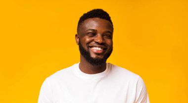 Samimi insani duygular. Sarı stüdyo arka plan üzerinde gülen sevimli kaygısız siyah adam Portresi