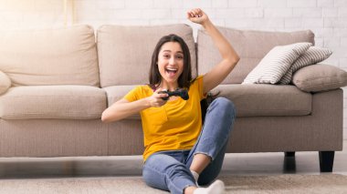 Evde hobilerin olsun. Oturma odasında video oyunu oynayan heyecanlı kız.