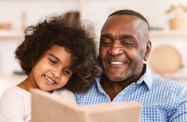 Aile kilitleri hobileri. Mutlu Afrikalı Amerikalı çocuk, dedesinin evde masal okumasını dinliyor.