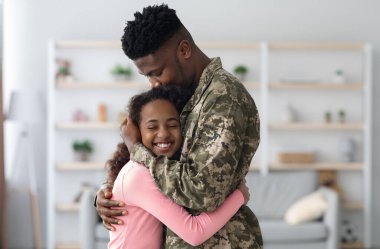 Askeri üniformalı Afro-Amerikan bir adamın, mutlu kıvırcık kız çocuğuna sarılışını, genç babasının askerlikten dönüşünü, kızına sarılışını, uzay fotokopisini...