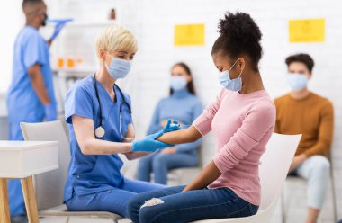 Coronavirus aşısı. Corona Aşısı Enjeksiyonu 'na karşı Aşı Yapan Afrikalı Genç Kız Kolunda Otururken Hastanede. Covid 19 Virüs Bağışıklık Kampanyası