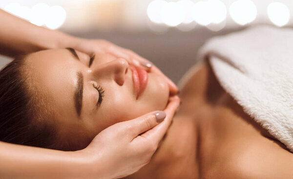 Уход за лицом. Массаж лица женщины в СПА салоне, крупный план
