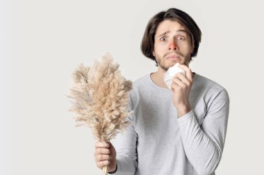 Alerji konsepti. Kırmızı burunlu, peçeteli ve buketli komik bir adam.