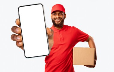 Güvenli Teslimat. Kurye, sarı stüdyo arkaplanının üzerinde duran paket kutusunu teslim etmek için bağlantısız kredi kartı tutuyor.