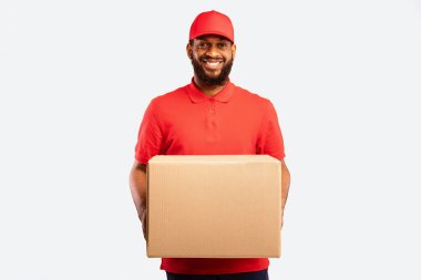 Hızlı Teslimat Servisi. Gülümseyen Kurye, Sarı Stüdyo Arkaplanından Malzemeleri Getiren Kameraya Karton Kutu Teklif Ediyor