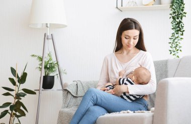 Eksiklik Konsepti. Güzel anne yeni doğmuş bebeği evdeki kanepede emziriyor.