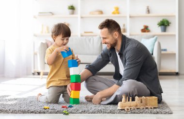 Oyun zamanı. Neşeli, sevgi dolu bir baba küçük oğluyla renkli bloklar oynuyor, büyük bir kule inşa ediyor, evde birlikte vakit geçiriyor.