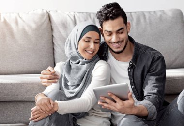 Müslüman aileyi sevmek, yeni bir dairede, kutuların arasında dijital tabletle oturmak, ev için mobilya almak, birlikte tasarım yapmak, kahve içmek ve sohbet etmek.