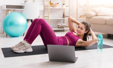 Tecrit sporları. Formda kız evde online egzersiz videosu için karın egzersizi yapıyor.