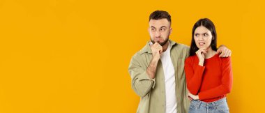 Kafkasyalı genç bir çift düşünceli ifadelerle birlikte duruyor. Kadın kırmızı bir kazak giyer, erkek ise yeşil bir tişört giyer.