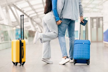 Bu genç çift havaalanında hassas bir anın tadını çıkarıyor. Birlikte heyecanlı yolculuklarına hazırlanırken el ele tutuşup gülümsüyorlar.