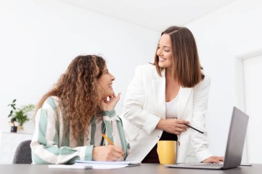 İki Avrupalı kadın, parlak bir şirket ofisinde ortak bir tartışmaya giriştiler. Bir kadın notlarla otururken, diğeri öngörülerini paylaşıyor, takım çalışmasını teşvik ediyor..