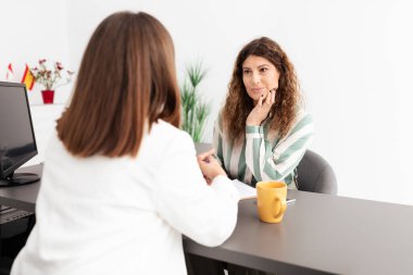 İki iş kadını çağdaş bir ofis masasında verimli bir konuşma yapıyorlar. Bir kadın dikkatle dinlerken, diğeri de kahve fincanlarıyla birlikte sezgilerini paylaşıyor..