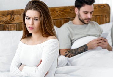 Tartışma ve kıskançlık. Yatakta akıllı telefondan sohbet eden bir adam var. Alıngan bir kız kollarını kavuşturup sırt sırta oturuyor. Bedava.