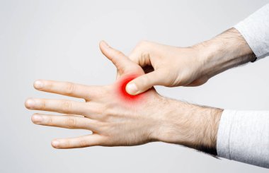 Kaslarda ve eklemlerde iltihap var. Gri arka planda izole edilmiş kırmızı eli tutan adam, stüdyo çekimi