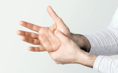 Vücut ağrısı. Adam, eklem iltihabı ya da yaralanma yüzünden elini eliyle bastırıyor. Kırpılmış, stüdyo çekimi, yakın çekim.