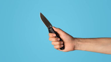 Mavi arka planda cep çakısı tutan genç adama yakın plan, boş alan. Panorama