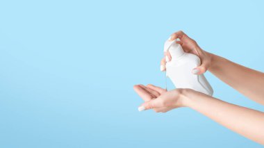 Kırpılmış bir bakış açısıyla, elinde şeker kutusundan sıvı sabun uygulayan bir kız, beyaz arka planda, kopyalama alanında. Panorama