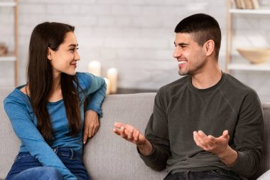 Güzel bir çift konuşuyor, evdeki kanepede oturuyor, rahat evlerinde güzel bir sohbet ediyorlar.