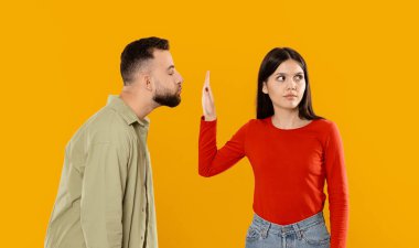 A young couple shares an affectionate moment but also experiences a disagreement. The man leans in close, while the woman raises a hand in a playful yet firm gesture. clipart