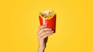 KHARKIV, UKRAINE - 4 Nisan 2020: Turuncu arka planda McDonalds 'tan küçük bir paket patates kızartması gösteren Millennial elemanı, yakın plan. Panorama