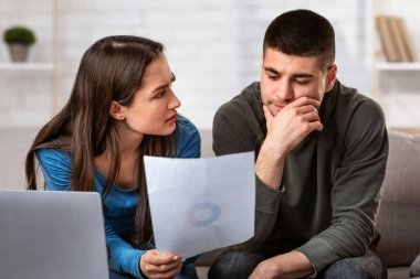 Mutsuz çift oturma odasında iç bütçeyi hesaplıyor, para biriktirmeye çalışıyor, stresli ve hayal kırıklığına uğramış görünüyor