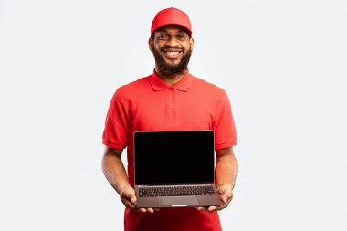 Teslimatçı, sarı arka planda boş ekranlı dizüstü bilgisayar tutuyor. Modelleme. Kurye ve Nakliye Servisi