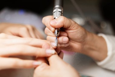 Yetenekli bir teknisyen şık bir salonda bir kadını şımartırken canlı bir tırnak cilası sürer. Atmosfer rahatlatıcı, son moda ve teknikleri sergiliyor..