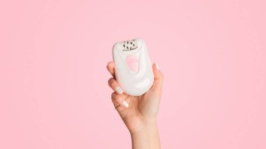 Tanımlanamayan milenyum kızı pembe arka plan, panorama üzerinde modern elektrikli epilatör gösteriyor.