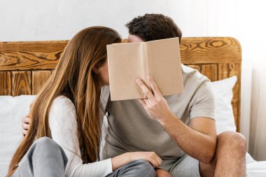 Koronavirüs karantinası sırasında yalnızlık çeken aşıklar. Millennial karı koca öpüşür ve kendilerini kitap ile örterler. Yatak odasının içinde, panoramada, boş alanda.