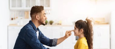 Babalar Günü Konsepti. Sevimli küçük Arap kızın portresi ve mutfakta birlikte oturan genç babasının sevgi dolu kızı, babası için el yapımı tebrik kartı, kenar manzaralı.