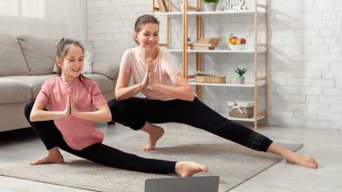 Çevrimiçi spor videosu eğitmeni. Mutlu milenyum anneleri ve genç kızları ağ germe kursları izliyor, evde egzersiz yapıyor, covid-19 tecridi sırasında spor yapıyor.