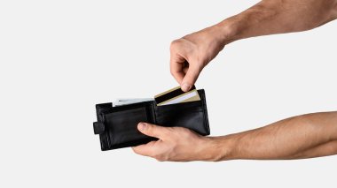 Genç adam açık gri arka planda cüzdanından kredi kartını çıkarıyor, kapat. Panorama