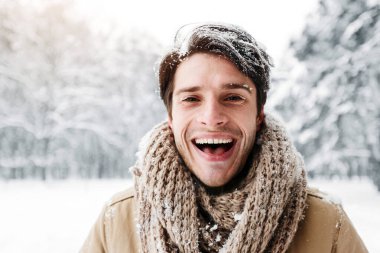 Kar Saçlı Neşeli Milenyum Adamı Karlı Orman 'da durup kış sabahının tadını çıkarırken kameraya bakıp gülüyor..