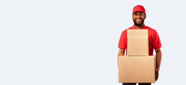 Ekspres teslimat. Siyah Kurye, elinde karton kutular ve paketler tutuyordu. Sarı Stüdyo Arkaplanda duruyordu. Çevrimiçi mağazadan mal getiriyordu..