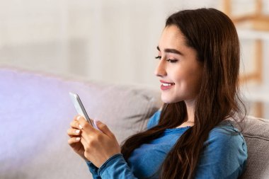 Ev Kavramında Kalın. Genç ve sevimli çift evde birlikte vakit geçiriyorlar, tablet ve cep telefonu kullanıyorlar.