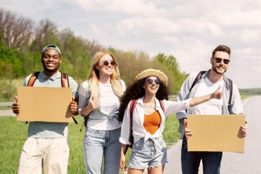 Boş tabelaları olan, otostop çeken, otostop çeken, otostop çeken, kopyalayan bir grup mutlu çoklu etnik arkadaş. Neşeli genç öğrenciler yaz gezisine çıkıyorlar, eğlenceli maceralar yaşıyorlar.