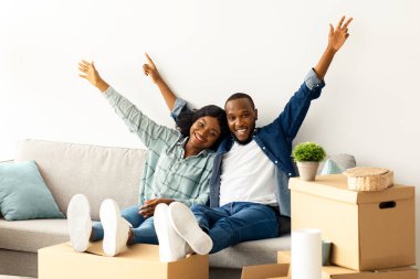 Mutlu Sahipler. Neşeli siyah eşler taşındıktan sonra koltuklarda dinleniyor, neşeli genç Afrikalı Amerikalı çift yeni daireye taşınıyor, Neşeyle el kaldırıyor, Boşluğu kopyalıyor