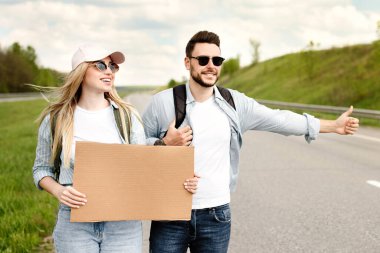 Otoyolda boş tabelayla dikilen mutlu bir milenyum çifti. Arabayı durduruyorlar, yolculuk yapıyorlar, tasarım için maket yapıyorlar. Yolculuk, otostop, birlikte otostop, yaz özgürlüğü konsepti.