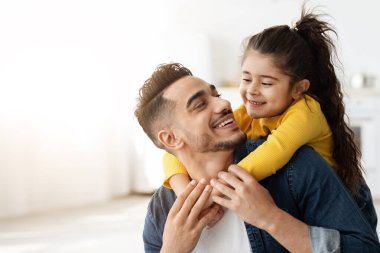 Sevimli, mutlu, küçük bir Arap kızı babasına arkadan sarılıyor ve gülüyor, genç, orta doğulu babası evde kızıyla bağ kuruyor, Müslüman ailesini seviyor, birlikte eğleniyor, yakınlaşıyor.