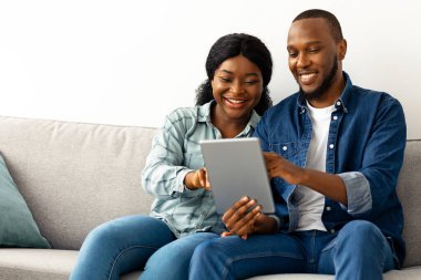 Yeni daireye taşındıktan sonra dijital tabletle çevrimiçi olan mutlu siyah çift, İnternet 'te mobilya satın almak için afro-amerikan eşlerini kullanıyor.