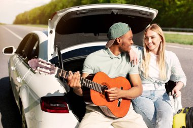 Seyahatleri sırasında bagajda otururken kız arkadaşına gitar çalan şefkatli siyahi bir adam. Çok ırklı bir milenyum çifti yolculuğun tadını çıkarıyor, yaz tatilinde eğleniyorlar.