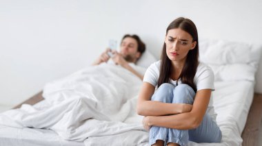 Mutsuz genç eş sadakatsizlikten şüpheleniyor ve kocasını aldatırken akıllı telefondan mesaj atıyor evde yatakta yatıyor. Yatak odasında oturan hayal kırıklığına uğramış bir kadına odaklan. Kıskançlık Konsepti.