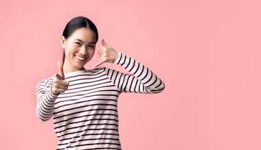 Ara beni. Neşeli, genç, Asyalı, eli kulağında, telefon taklidi yapan ve kamerayı işaret eden genç bir bayan, Pembe Stüdyo Arkaplanındaki İletişim Pozitif Koreli Kadın Davetiyesi,