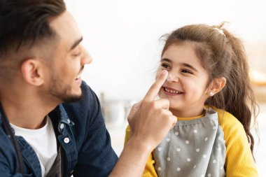 Pişirme Eğlencesi. Sevimli küçük kız ve Arap babası mutfakta hamur işi pişirirken, Orta Doğulu babalar kızlarının burnunu un ile boyar, yakın plan çekimler yapar.