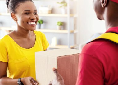 Alışveriş Teslimatı. Siyah Erkek Kurye Evinin Kapısında Bekleyen Neşeli Kadın Müşteriye Büyük Kutu Veriyor. Üniformalı adam Afrikalı Amerikalı kadına paket teslim ediyor. Seçici Odaklanma