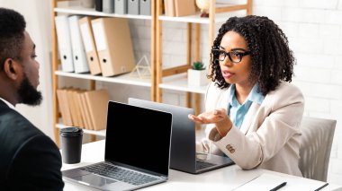 Ciddi siyahi kadın şirket ofisindeki erkek arkadaşıyla konuşuyor, ortak proje hakkında sorular soruyor, kopyalama alanı. İş yeri konseptinde takım çalışması ve işbirliği