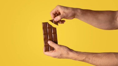 Çikolata kıran adamın yakın plan görüntüsü, turuncu arka plan. Uzayı kopyala Panorama